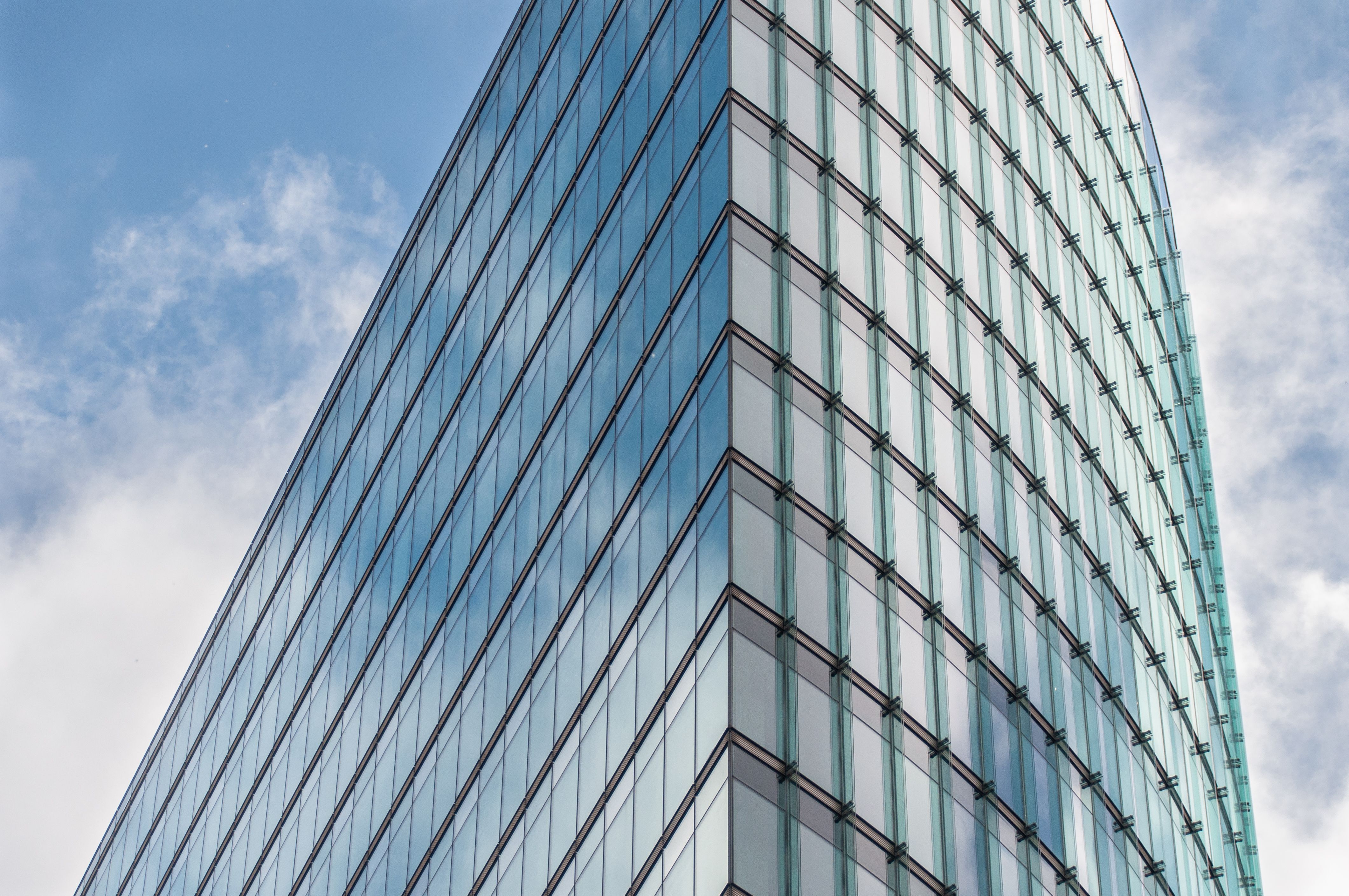 Sleek glass corporate skyscraper reflecting the sky, representing a large corporate legal opponent