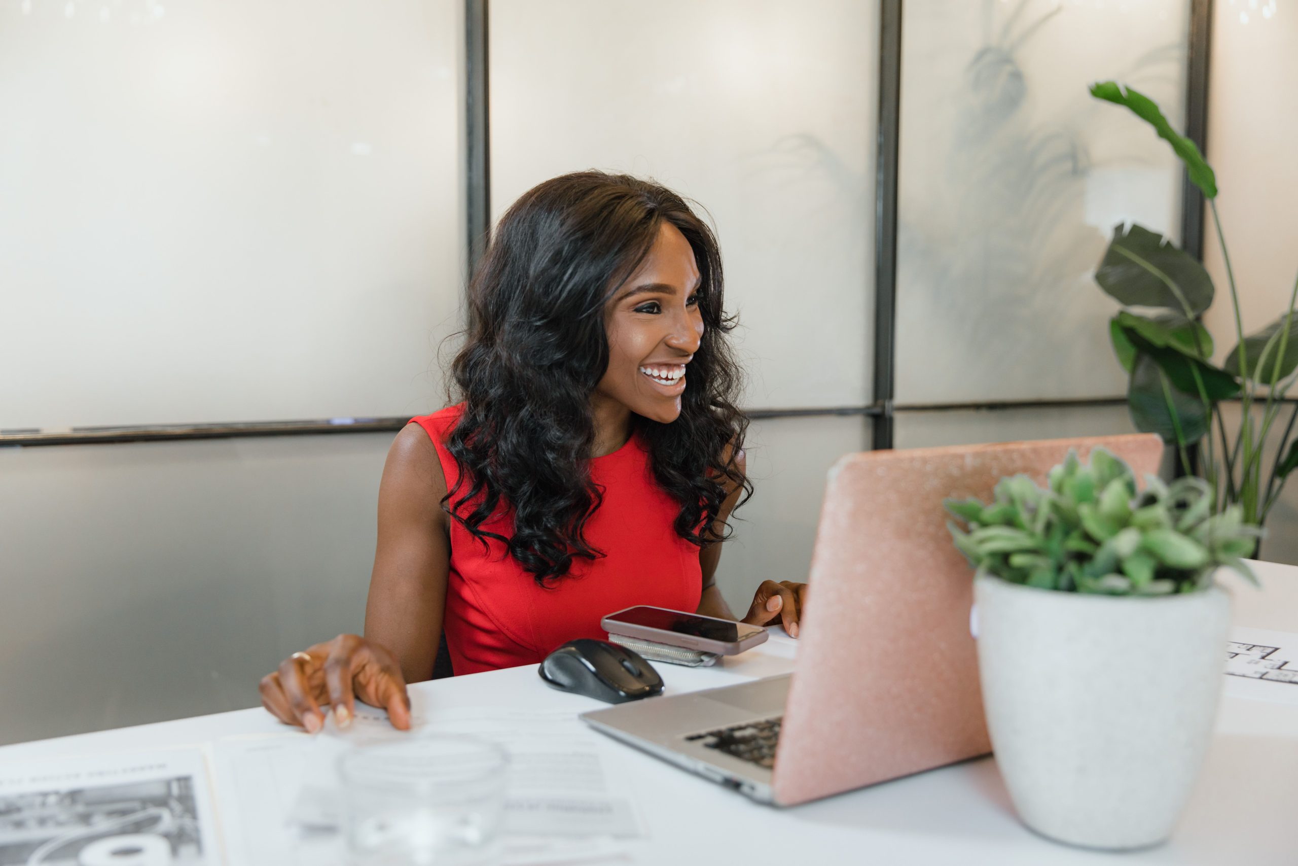 Small business owner working on a laptop and smartphone at her desk to improve her website's search visibility