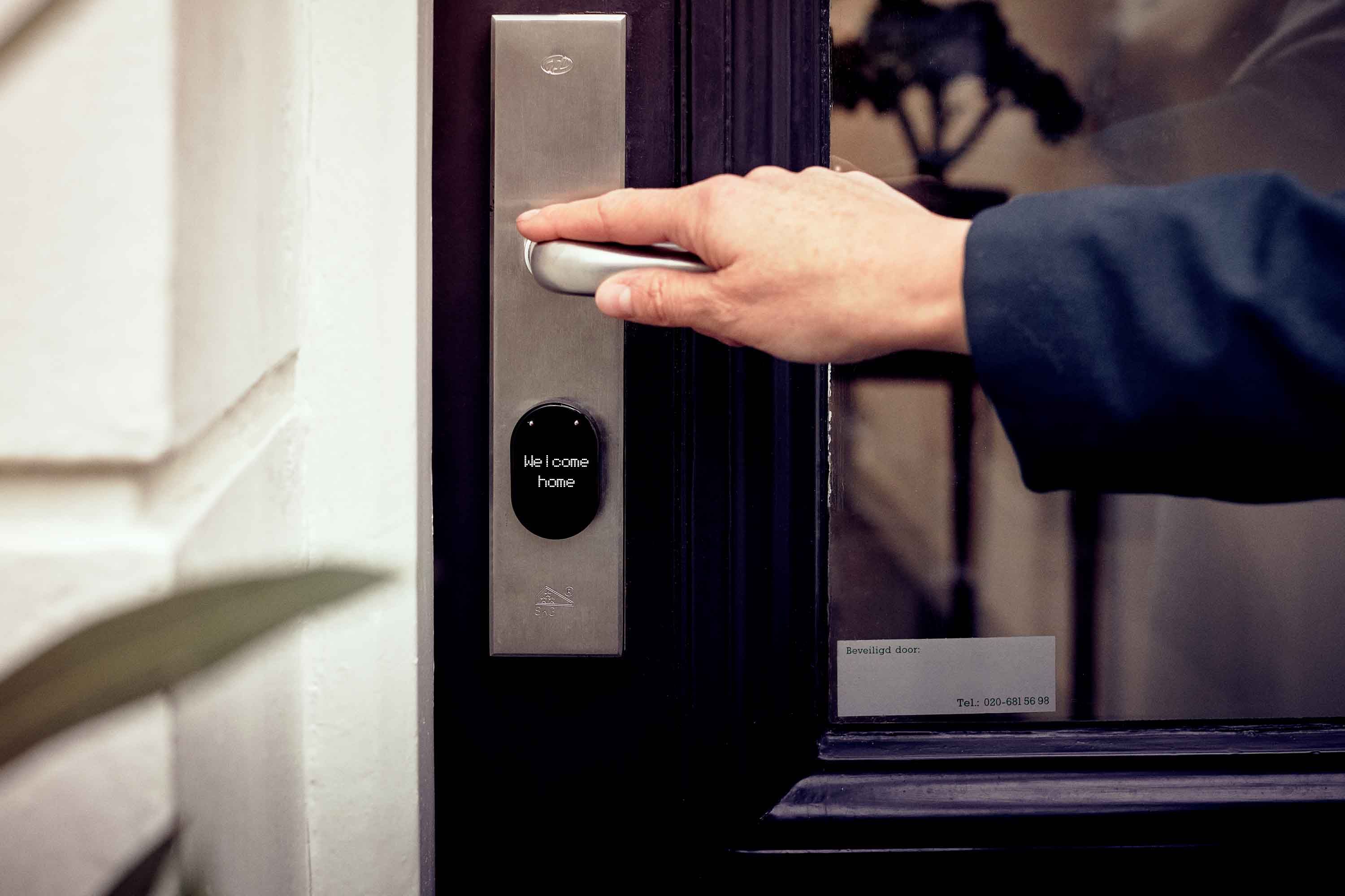 Hand opening a smart home door with a digital access panel